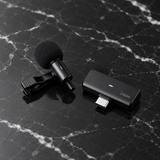 Wireless lavalier microphone on black marble surface, premium studio product shot